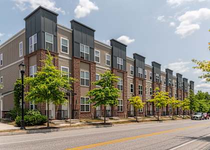 A row of apartment buildings with trees in front.